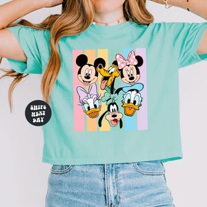 A woman wearing a turquoise crop top with a graphic of Disney characters on it.
