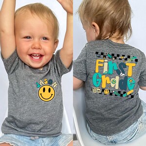 A smiling baby boy wearing a gray t-shirt with a smiley face and the name "JASON" printed on it.