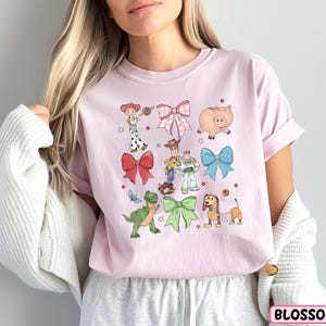 a woman wearing a pink shirt with cartoon characters on it