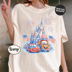 A person is wearing a white t-shirt with a graphic design featuring a castle, cars, and fireworks.