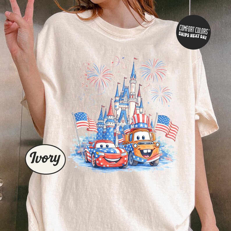 A person is wearing a white t-shirt with a graphic design featuring a castle, cars, and fireworks.
