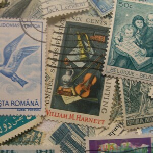 May include: A collection of vintage postage stamps, featuring various designs and countries. Stamps include a blue bird, a still life with a violin, and a stamp with a family reading. The stamps are in various colors and sizes.