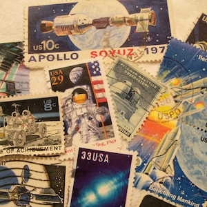 May include: A collection of vintage space-themed postage stamps featuring images of rockets, astronauts, and the Earth. The stamps are from the United States Postal Service and feature the text "Apollo Soyuz 197", "A Decade of Achievement", "Benefiting Mankind", and "Palomar Mountain Observatory".