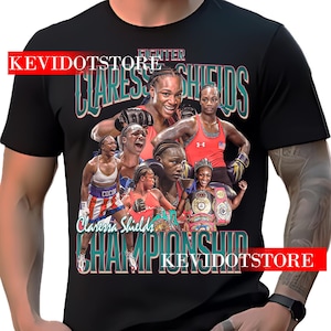 May include: Black t-shirt featuring a collage of images of Claressa Shields, with the text "Claressa Shields Championship Fighter" in teal and white. The shirt includes images of Shields in boxing gear and championship belts.