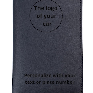 Op de afbeelding: Een donkerblauwe leren portemonnee met bovenaan de tekst "CUSTOMIZE". Een cirkelvormig gebied is gelabeld met "The logo of your car". De onderkant van de portemonnee luidt "Personaliseer met uw tekst of kenteken".