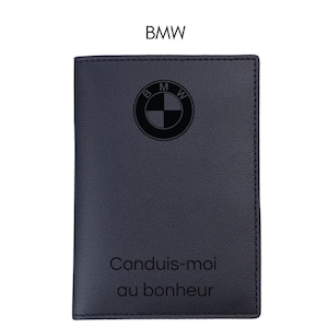 Puede incluir: Cartera de cuero azul oscuro con el logotipo de BMW en relieve en la parte delantera. La cartera tiene el texto "Conduis-moi au bonheur" debajo del logotipo. La palabra "BMW" está en la parte superior.