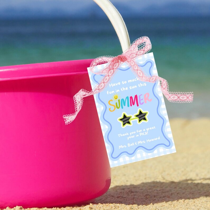 May include: A pink plastic bucket with a blue and white tag attached. The tag has a colorful "SUMMER" graphic with sunglasses and the text "Have so much fun in the sun this SUMMER. Thank you for a great year in PK3. Mrs. Ball & Mrs. Howard."