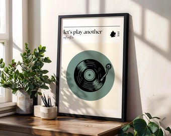 Könnte beinhalten: Ein gerahmter Druck mit einer Vintage-Illustration eines Plattenspielers und dem Text "Let's play another record". Der Hintergrund ist hellbeige mit einem türkisfarbenen Kreis um den Plattenspieler.