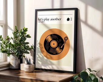 Könnte beinhalten: Ein schwarzer gerahmter Druck mit einer Vintage-Illustration eines Plattenspielers auf einem hellorangen Hintergrund. Der Text "Let's play another" und "record" ist oben auf dem Druck in Schwarz gedruckt.
