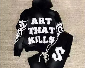 May include: Black hooded sweatshirt and matching sweatpants with the phrase "ART THAT KILLS" and a tribal design printed in white.