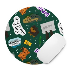 Könnte beinhalten: Rundes Mauspads mit einem skurrilen Design auf dunklem grünen Hintergrund. Das Design umfasst Zeichentricktiger, ein Saxophon, einen schwarzen Hund und Text mit der Aufschrift "I'm a good boy" und "Niagara Pokpo". Eine weiße Computermaus befindet sich auf der rechten Seite.