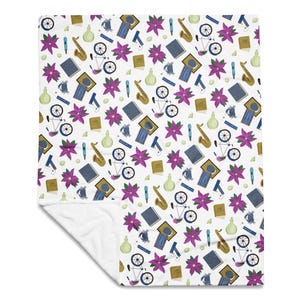 May include: White throw blanket with a repeating pattern of bicycles, saxophones, books, microphones, purple flowers, and green pear-shaped objects. The blanket has a soft, plush texture.