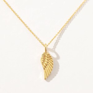 Puede incluir: Un collar de cadena de oro con un delicado colgante de ala de oro.