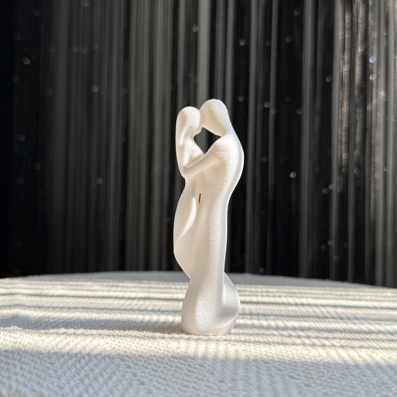 Side view of the Soulmates Lovers Sculpture, depicting a tender embrace between two figures. The 3D printed design captures a moment of affection, standing at 15cm.