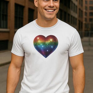 Op de afbeelding: Wit T-shirt met een regenboogkleurig discobal hartontwerp. Het hart heeft een glinsterend, reflecterend oppervlak met een kleurengradatie. Het shirt heeft korte mouwen en is gemaakt van een zacht materiaal.