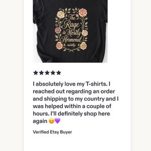 Może przedstawiać: Czarny t-shirt z kr&oacute;tkim rękawem z centralną grafiką wieńca z r&oacute;żowych, ż&oacute;łtych i białych r&oacute;ż. Tekst wewnątrz wieńca brzmi, The Rage is Mostly Hormonal, a słowo mostly powt&oacute;rzono mniejszą czcionką tuż pod gł&oacute;wnym napisem.