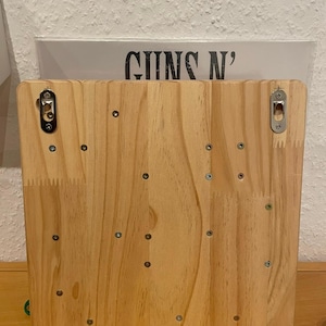 May include: A wooden backboard with multiple screws and two metal hooks. The backboard is light brown and has a natural wood grain.