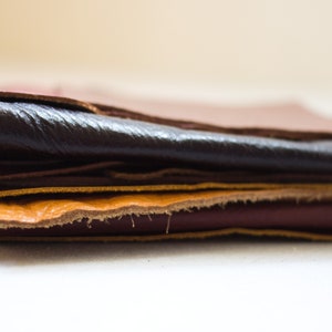 May include: A stack of leather pieces in various shades of brown, from light tan to deep burgundy. The textures vary, with some pieces appearing smooth and others showing a rough, unfinished edge. Ideal for crafting.