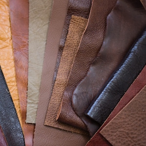 May include: A collection of leather swatches in various shades of brown, tan, and black. The textures range from smooth to heavily grained, showcasing the natural variations in the material. Ideal for crafting projects.