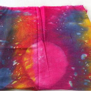 May include: A vibrant tie-dye fabric with shades of pink, yellow, orange, and blue. The fabric has a mottled, abstract pattern.