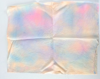 Puede incluir: Un trozo de tela doblado con un patrón de tie-dye en tonos de rosa, azul y amarillo.