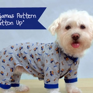 Op de afbeelding: Een witte hond die een grijze en blauwe pyjama draagt met een vrachtwagenpatroon. De pyjama heeft een knoopsluiting. De tekst "Dog Pajamas Pattern 'Button Up'" staat op een blauwe banner.