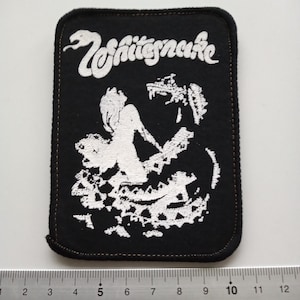 May include: Black rectangular patch with a white illustration of a woman and a snake, with the band name "Whitesnake" in white script. The patch has a stitched border and is approximately 4 inches wide.