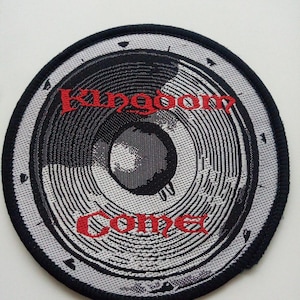 Op de afbeelding: Ronde patch met een luidsprekerontwerp in grijstinten en zwart. De tekst "Kingdom Come" is rood geborduurd. De patch heeft een zwarte rand en een witte achtergrond.