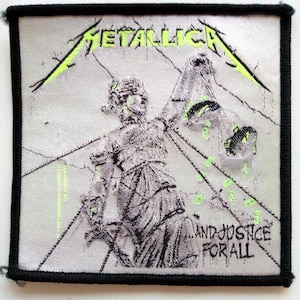 Può includere: Una toppa ricamata in bianco e nero con il nome della band "Metallica" e il titolo dell'album "...And Justice For All" in testo verde. La toppa presenta una statua argentata della Giustizia che tiene una bilancia.