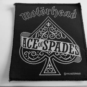 May include: Black fabric patch with white embroidered text and design. The text reads "Motorhead Ace of Spades" with a stylized spade design. The copyright symbol and "1993 Motorhead" are also embroidered in white.