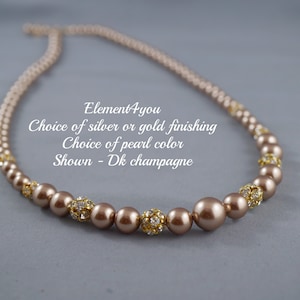 May include: A champagne-colored pearl necklace with gold accents. The necklace is made of small pearls and gold beads. The text on the image reads: "Element4you Choice of silver or gold finishing Choice of pearl color Shown - Dk champagne"