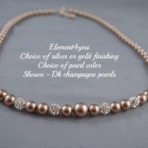 May include: A brown pearl necklace with silver or gold accents. The necklace is made with champagne colored pearls and has a choice of silver or gold finishing.  Element4you.