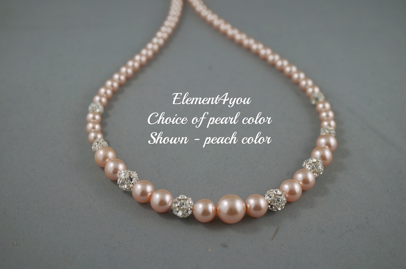 May include: A peach-colored pearl necklace with silver rhinestone accents.  Element4you Choice of pearl color Shown - peach color