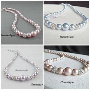 May include: Four necklaces with pearl beads and rhinestone accents. The necklaces are in four different colors: pink, light blue, lavender, and light brown.