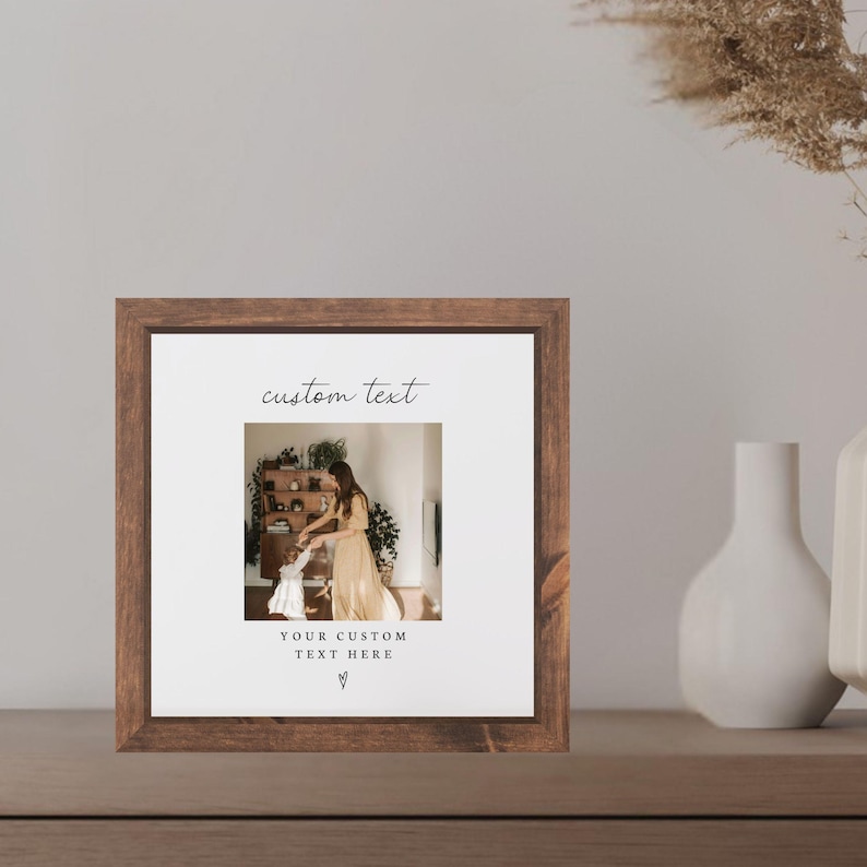 Puede incluir: Marco de fotos cuadrado de madera con un paspart&uacute; blanco. El marco contiene una fotograf&iacute;a de una persona y un ni&ntilde;o. Las palabras "custom text" y "YOUR CUSTOM TEXT HERE" est&aacute;n impresas en escritura negra.
