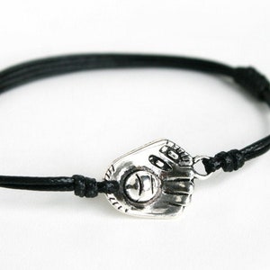 May include: A black leather cord bracelet with a silver baseball glove charm.