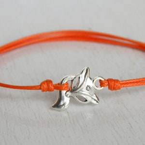 May include: An orange string bracelet with a silver fox charm. The charm is detailed and has a small hole for the string to pass through.