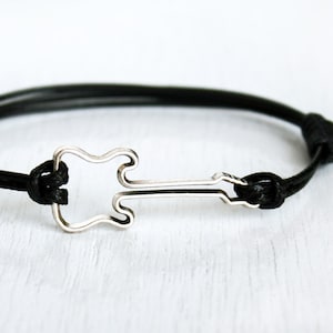 May include: A black cord bracelet with a silver guitar charm.