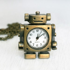 May include: A gold-toned robot-shaped pocket watch with a white face and black hands. The watch has a chain attached to it.