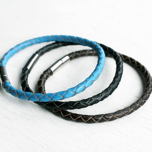 May include: Three braided leather bracelets in blue, black, and brown. The bracelets have a magnetic clasp.