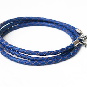 May include: A blue leather cord necklace with a silver clasp. The cord is braided and has a subtle brown undertone.