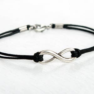 May include: A black cord bracelet with a silver infinity symbol charm.