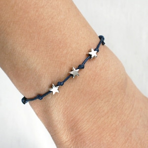 May include: A navy blue string bracelet with silver star charms.