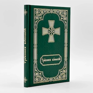 May include: A green book with gold embossed detailing and text. The cover features a gold cross design within an ornate frame. The spine displays vertical text in gold. The book's title is also in gold lettering.