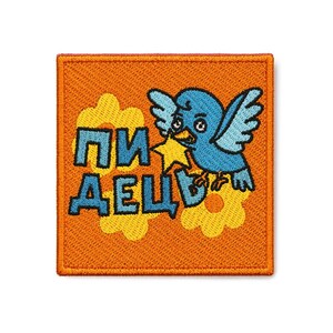 May include: A square embroidered patch with an orange background featuring a blue bird holding a yellow star. The design includes two yellow flowers and the Cyrillic text "ПИДЕЦ" in blue letters. The patch has a red border and a textured finish.