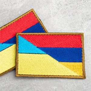 May include: Two rectangular embroidered patches featuring a geometric design with horizontal bands of red, blue, and yellow. The patches have a thick, dark-colored stitched border and a textured surface created by dense, multi-colored thread work.