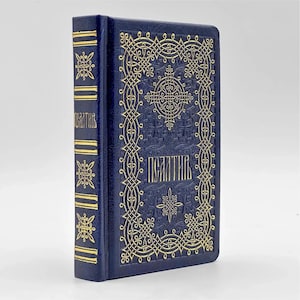 May include: A navy blue book with gold embossed lettering and decorative patterns. The spine features gold horizontal lines and a vertical inscription. The cover displays an ornate, symmetrical design with the title in gold lettering.