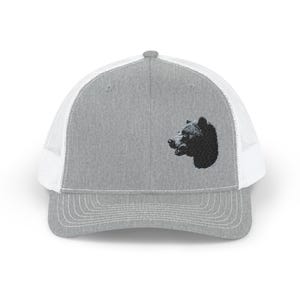 May include: Grey trucker cap with a white mesh back and a black bear head embroidered on the front. The cap has a curved peak and a snapback closure. A classic accessory for outdoor activities or casual wear.