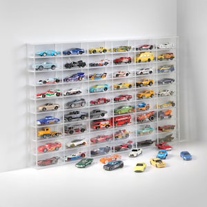 Op de afbeelding: Een transparante acryl displaykast met meerdere planken om speelgoedauto's op te bergen en te presenteren. De kast is gevuld met een verscheidenheid aan kleurrijke speelgoedauto's, waaronder rode, blauwe, gele en groene auto's. Er zijn ook een aantal zwarte en witte auto's in de displaykast.