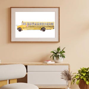 May include: Watercolor painting of a yellow school bus with black stripes and windows. The bus has a stop sign and black wheels. The artwork is framed in a light brown wooden frame and hangs on a beige wall.